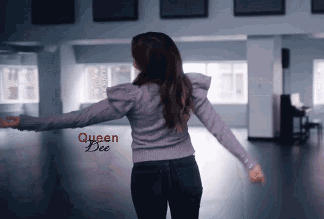 a woman in a purple sweater is dancing in a room with queen bee written on the bottom