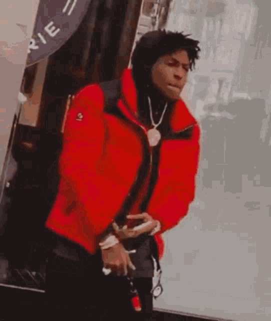 a man in a red jacket is standing in front of a purple sign that says " rie "