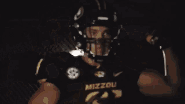 a football player wearing a helmet and gloves is holding a flashlight .