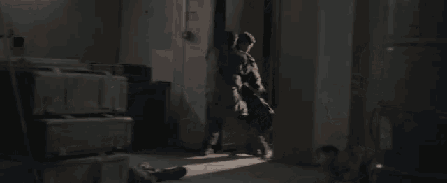 a man is laying on the floor in a dark room with a stack of boxes in the background .