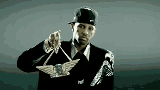 a man in a suit and hat is holding a gold winged belt .