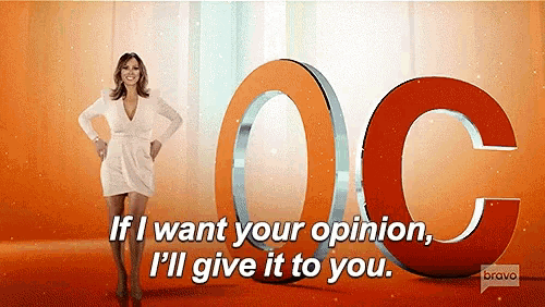 a woman in a white dress is standing in front of a large orange letter oc