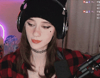 a woman wearing headphones and a choker looks at the camera