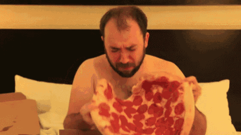 a shirtless man is eating a pepperoni pizza