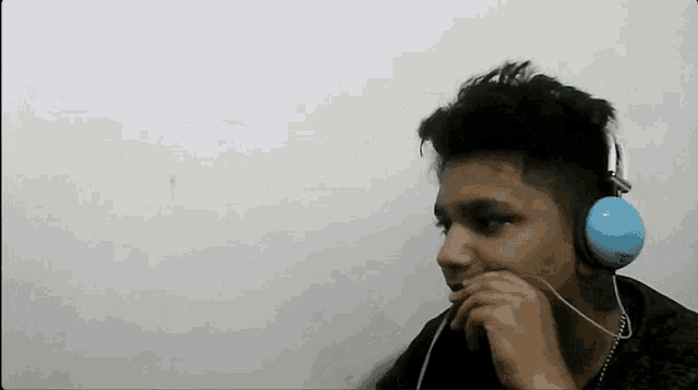 a young man wearing a pair of blue headphones looks at something