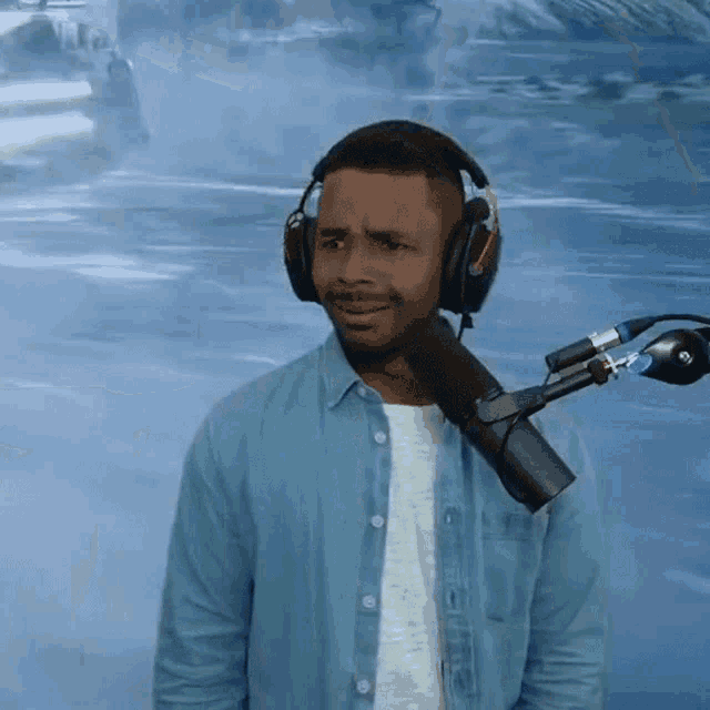 a man wearing headphones stands in front of a microphone with a surprised look on his face