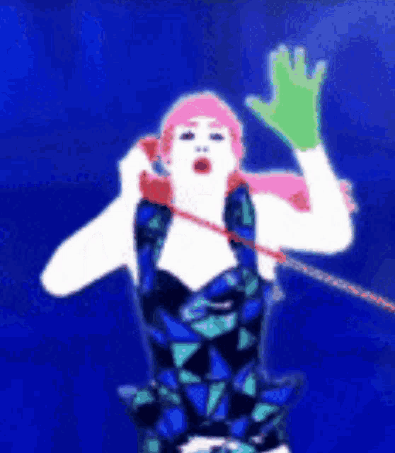 a woman with pink hair is talking on a telephone and waving