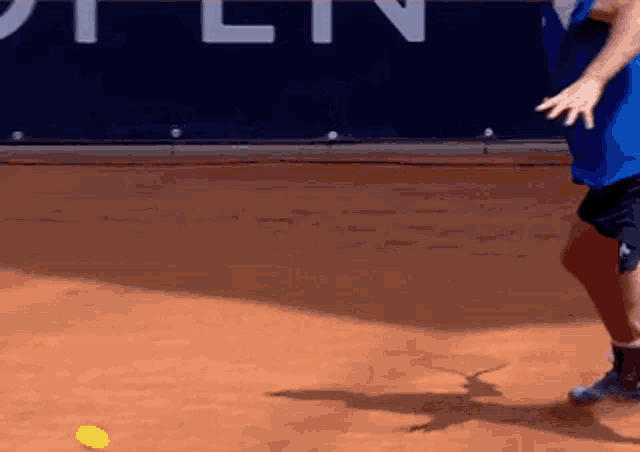 a man in a blue shirt is playing tennis on a court
