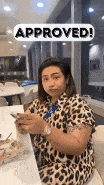 a woman is sitting at a table looking at her phone .