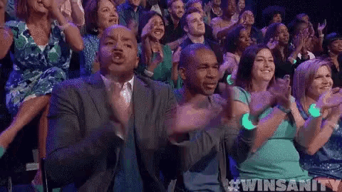 a crowd of people are clapping their hands in a theatre .