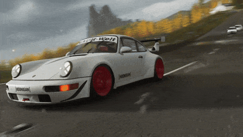 a white car with red wheels is driving down a road with a sign that says high-welt