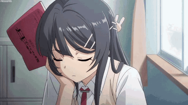 a girl is sleeping with a book on her head that says ' tokyo ghoul ' on it