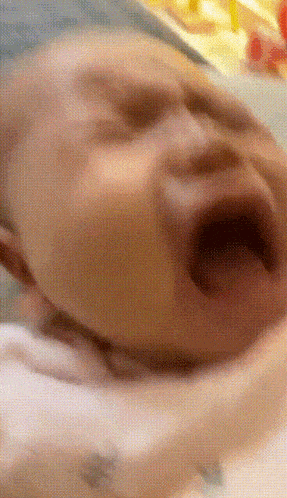 a close up of a baby 's face with its mouth open