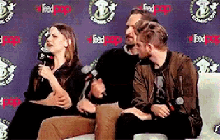 three people are sitting in front of a wall that says feed pop