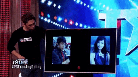 a man stands in front of a screen that has a picture of a man and a picture of a woman on it