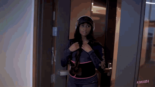 a woman wearing headphones and a hat is standing in a doorway with the word kimora on the bottom