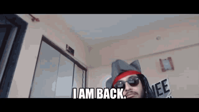 a man is wearing a hat and sunglasses and says i am back
