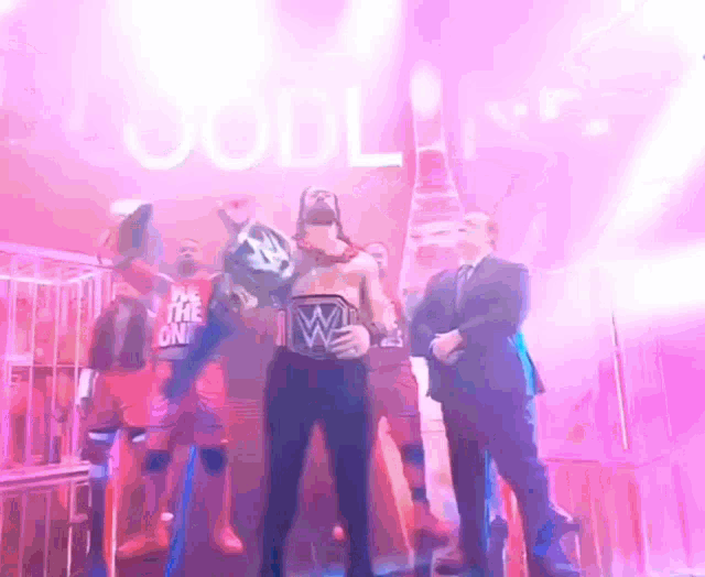 a man in a wrestling ring holding a world heavyweight championship belt with the letter w on it