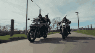 two people on motorcycles wearing bunny hats are riding down a road