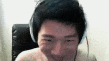 a shirtless man wearing headphones is making a funny face while sitting in a chair .