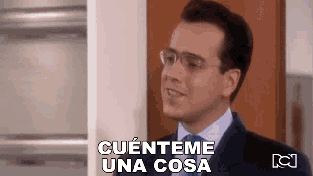 a man wearing glasses and a suit says cuenteme una cosa