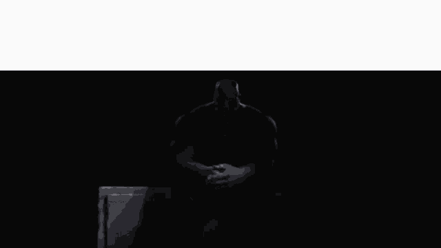 thanos is sitting in a chair in the dark .