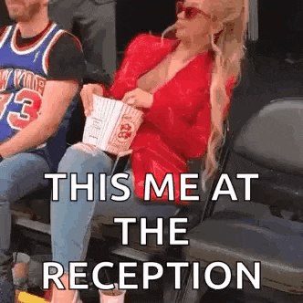 a woman is sitting in a stadium holding a bag of popcorn and smoking a cigarette .