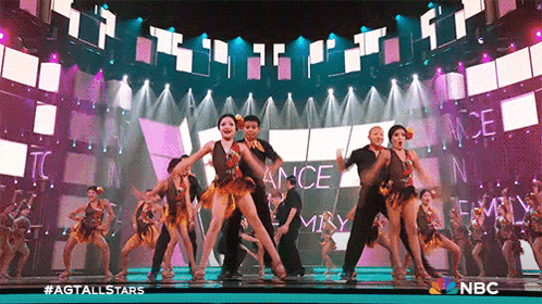 a group of people are dancing on a stage in front of a large screen that says ance