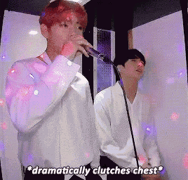 a man singing into a microphone with the words dramatically clutches chest