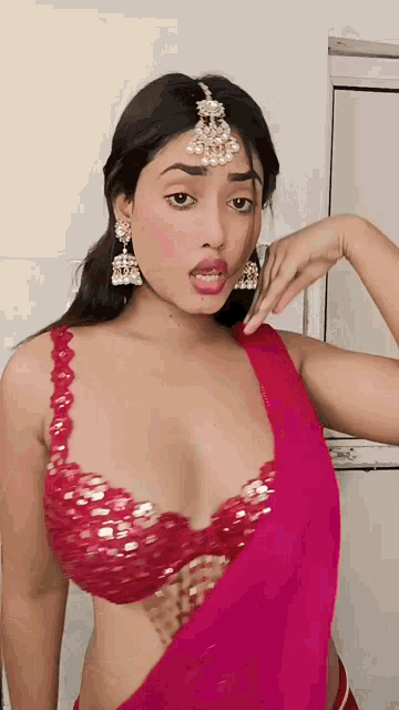 a woman wearing a red bra and earrings is making a face