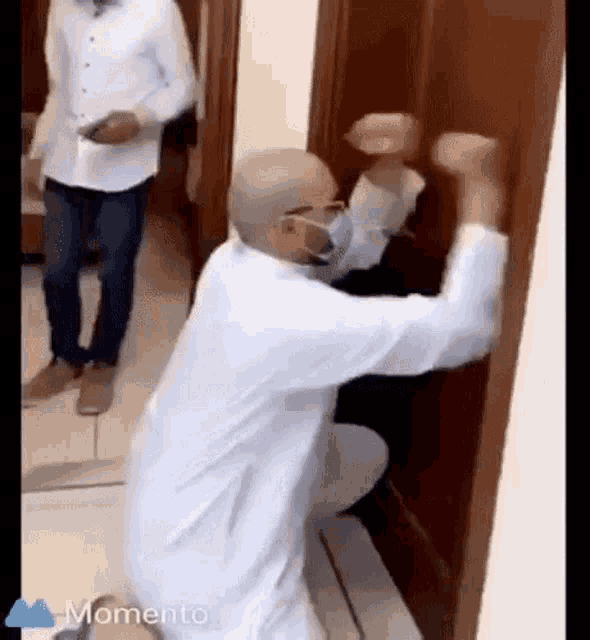 a man wearing a face mask is kneeling down in front of a door .