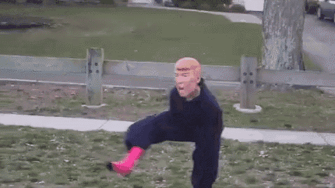 a man wearing a donald trump mask is dancing on a field .