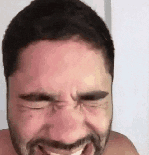 a shirtless man with a beard is making a funny face with his mouth open .