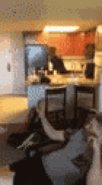 a blurry picture of a person sitting on a couch in a living room with a kitchen in the background .