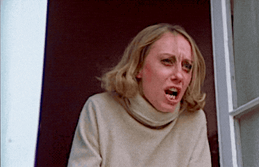 a woman with a turtleneck sweater is making a funny face with her mouth open