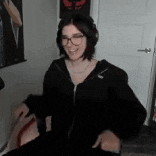 a woman wearing glasses and headphones is sitting in a chair and smiling .