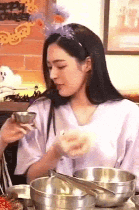 a woman is sitting at a table with bowls of food and a bowl of soup .