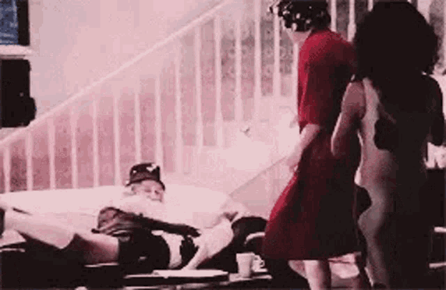 a woman is standing next to a man laying on the floor .