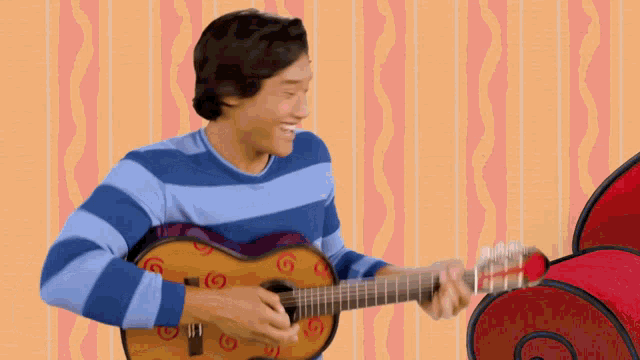 a man in a blue striped shirt is holding a guitar