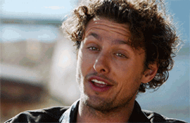 a close up of a man 's face with curly hair and a beard