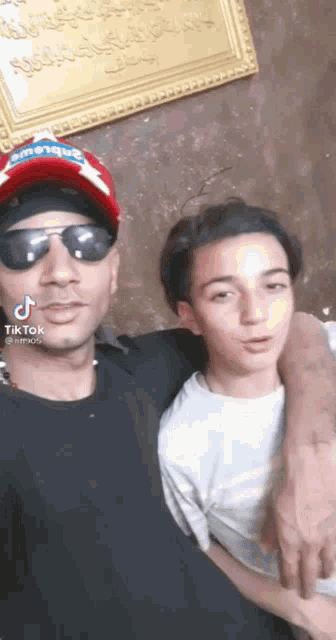 a man and a boy are posing for a picture and the boy is wearing sunglasses .