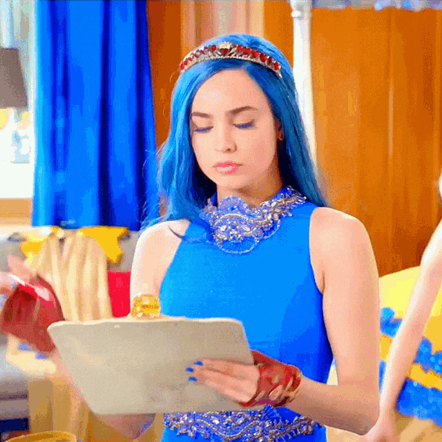 a woman with blue hair is holding a tablet in her hand