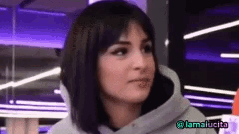 a woman wearing a grey hoodie is making a funny face .