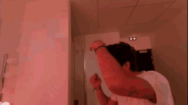 a man in a white shirt is looking at himself in the mirror