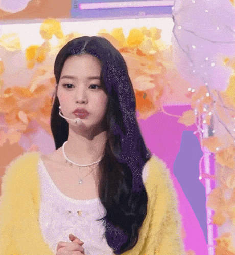 a woman with purple hair is wearing a yellow sweater and a white top