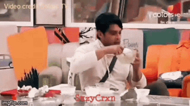 a man is sitting at a table drinking from a cup