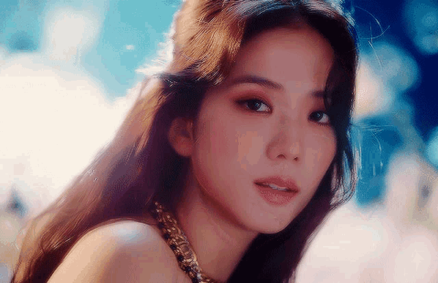 a close up of a woman 's face wearing a gold necklace