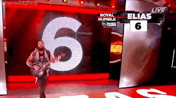 a man is playing a guitar on a stage in front of a sign that says elias 6 .
