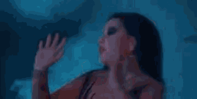 a group of women in red dresses are dancing in a dark room in front of a mirror .