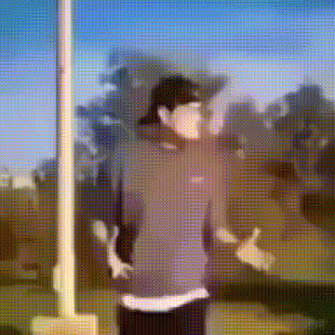 a blurry picture of a man standing in front of a pole with his arms outstretched